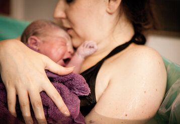 Mutter liegt mit neugeborenem Baby in einer Geburtswanne
