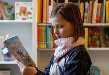 Ein Mädchen liest in dem Buch, dass es am Welttag des Buches gratis gibt
