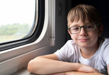 Ein Junge mit Brille sitzt im fahrenden Zug